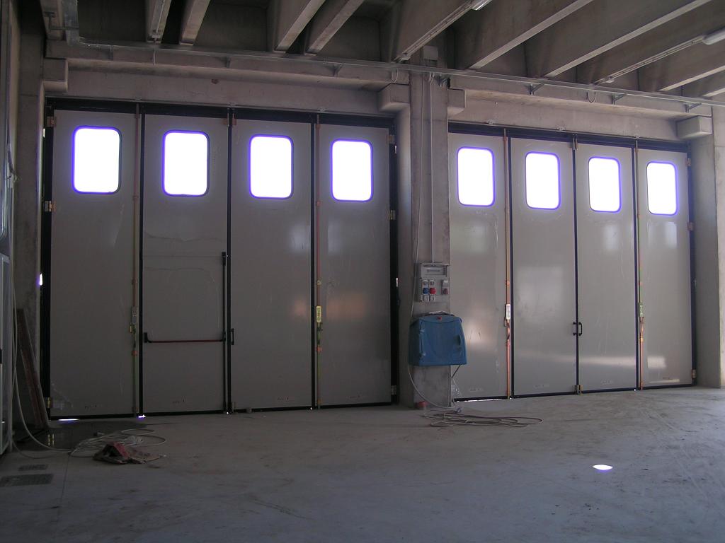 portone industriale a libro bianco con finestrature e porta d'ingresso con maniglia antipanico