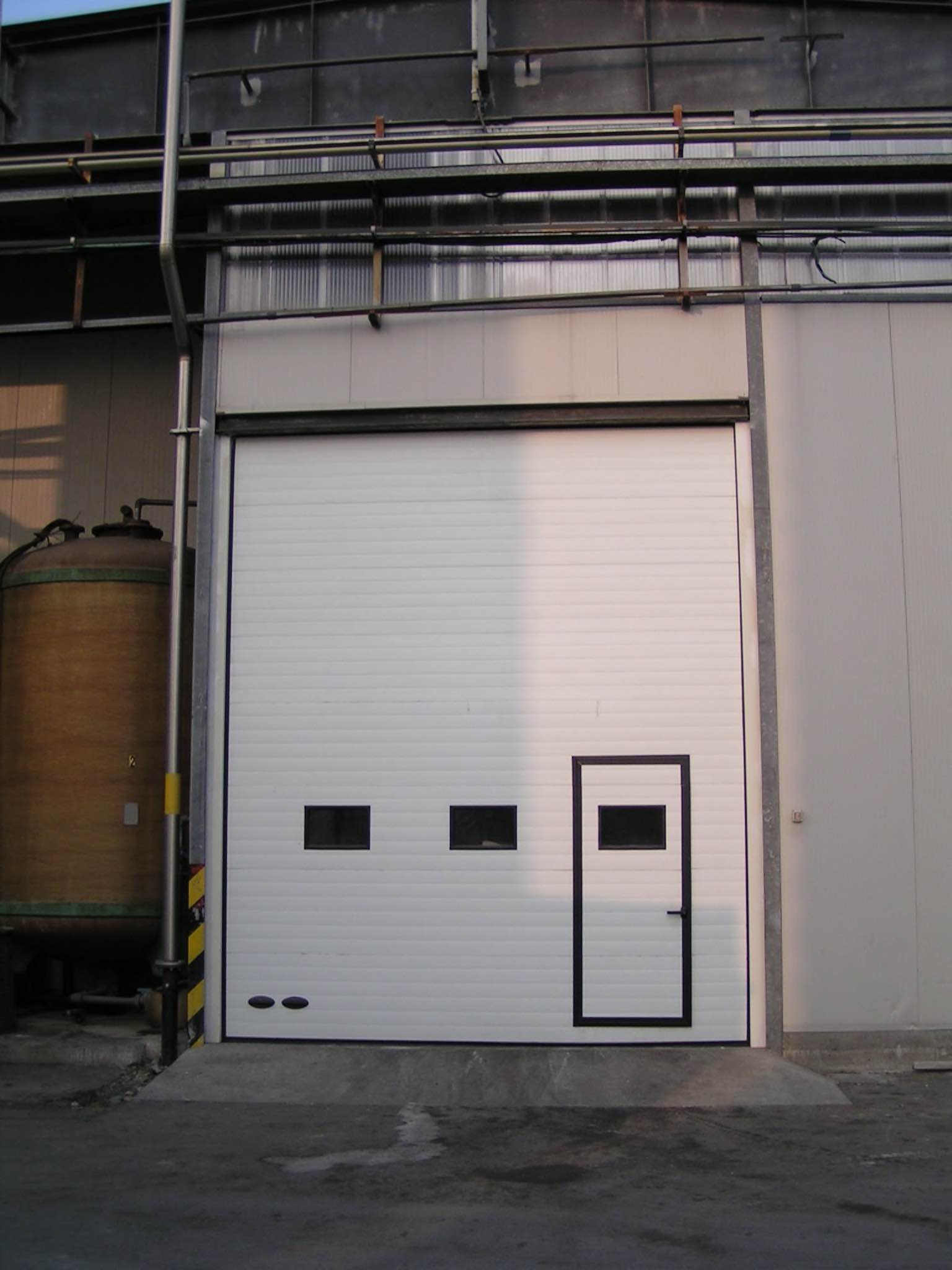 portone industriale sezionale bianco con porta d'ingresso