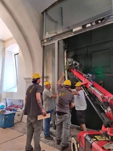 Lenta movimentazione in spazi ostici dei vetri laterali alti 4,5 m della bussola automatica a Palazzo Trentini