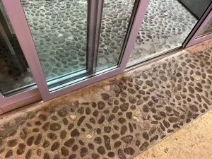 Dettaglio della bussola automatica in vetro a Palazzo Trentini: guide incassate nel pavimento storico